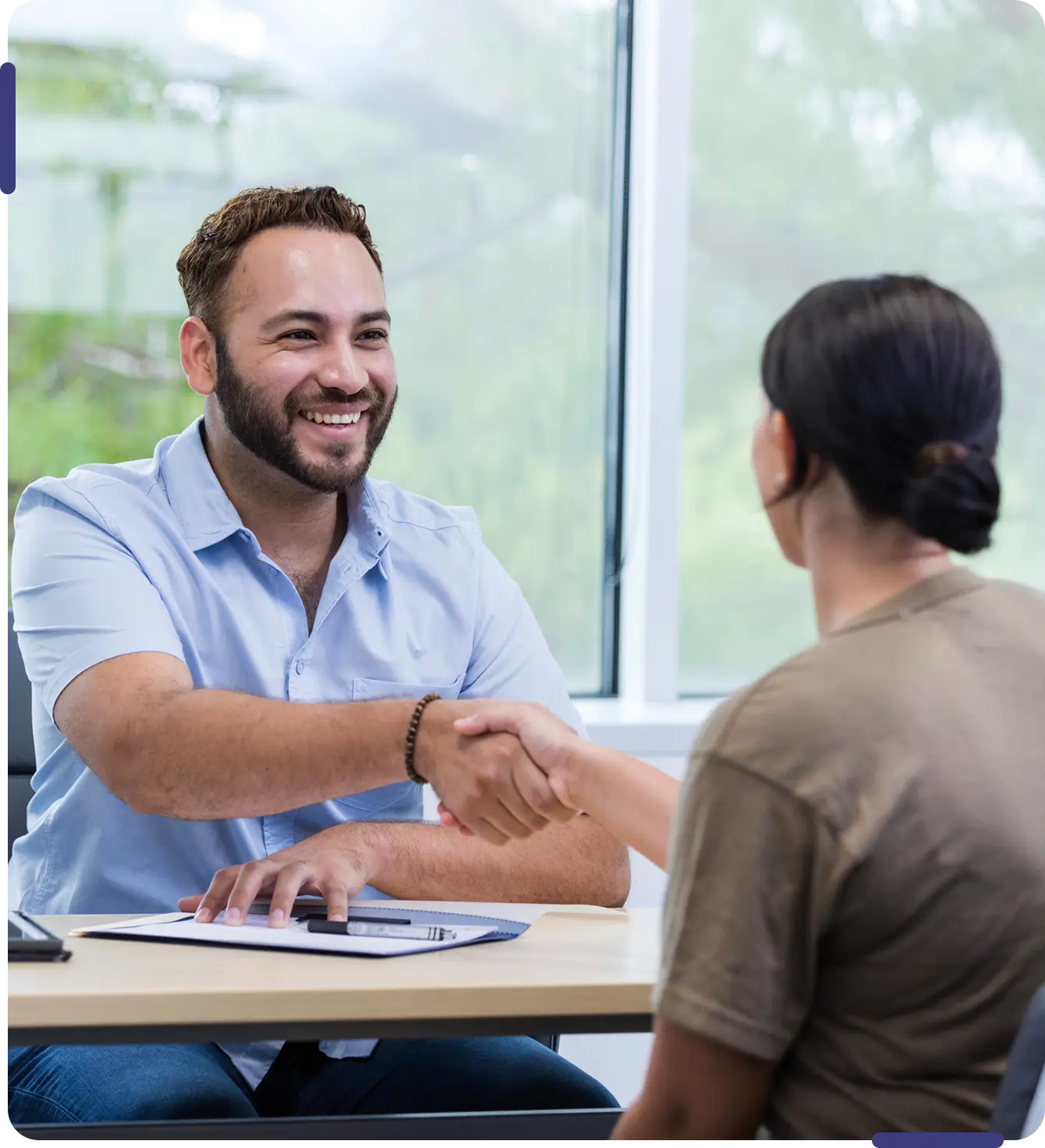Two people shaking hands in office.